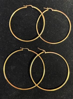 trois paires de boucles d'oreilles créoles en or sur un fond noir