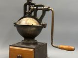 un vieux moulin à café avec un manche en bois sur fond gris