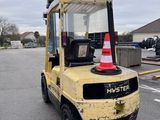 a yellow fork truck parked in a parking lot with a cone on top of it