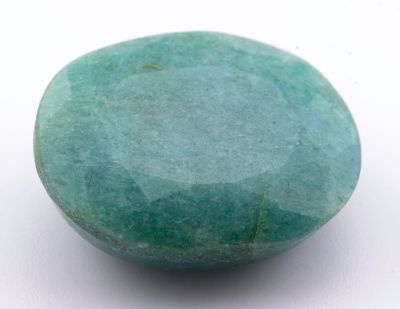 une pierre vert turquoise posée sur une surface blanche, avec un fond blanc