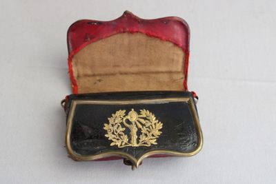 un petit étui noir et rouge orné d'un emblème doré