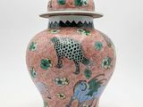 an image of a pink and green vase with a lid on a white background