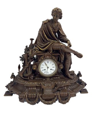une statue en bronze représentant un homme assis sur un banc, avec une horloge