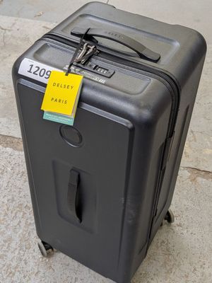 un bagage posé par terre, avec une étiquette de prix accrochée dessus