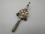 an antique silver spoon with a green handle on a white surface