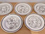 six assiettes ornées de personnages de dessins animés, posées sur une table en bois