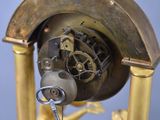 a gold clock with a key in the middle of it