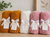 four towels with tags on them sitting on a table next to a potted plant