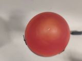 a red ball with a black handle sitting on a white surface