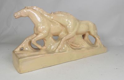 cream colored ceramic sculpture of two horses running on a wooden base