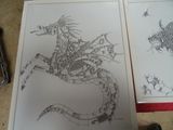 dessin d'un dragon sur une feuille de papier, à côté d'une paire de ciseaux