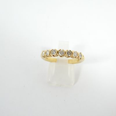 gros plan d'une bague en or avec des diamants sur une surface blanche