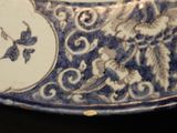 a close up of a blue and white plate with a bird on it