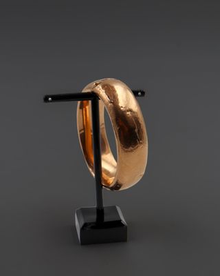 un gros plan d'une bague en or posée sur un socle noir