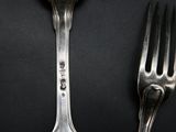 two forks and a spoon on a black table
