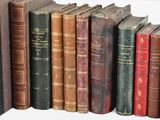 many old books lined up in a row on a shelf