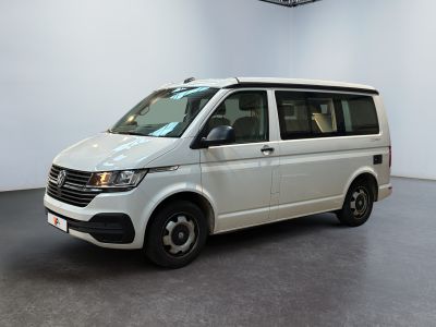 La camionnette blanche est garée dans une pièce blanche au sol noir.