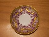 a purple and white plate with a gold rim on a wooden table