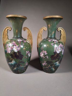two green vases with flowers on them sitting on a table