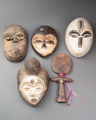 Plusieurs masques africains sont accrochés au mur d'une pièce.