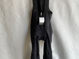 black bib shorts hanging on a hanger on a white wall