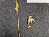 un gros plan sur un collier en or orné d'un dauphin et d'un poisson