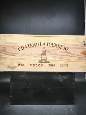 une caisse en bois sur laquelle est accrochée une pancarte indiquant « Château Tourbey »