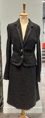a dress and jacket on a mannequin stand in a store