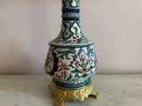 a blue and white vase with a gold base on a table
