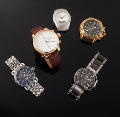 three watches are sitting on a black surface with a watch in front of them