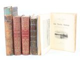 several old books sitting on top of each other on a white surface