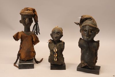 Trois statuettes en bois habillées de tuniques et de bonnets…