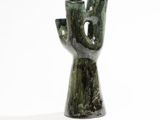 une sculpture verte représentant une main percée d'un trou au milieu