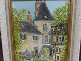 an oil painting of a house in a frame on a wooden floor