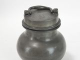 a black pot with a handle on a white surface