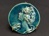 une photo d'une broche bleue et verte représentant une tête de femme