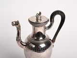a silver tea pot with a handle on a table