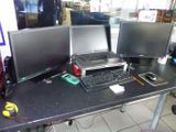 three monitors and a laptop on a desk in a room
