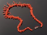 a red coral necklace on a black surface with a silver clasp