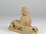 a statue of a woman sitting on a sled on a white surface