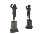 une paire de figurines en bronze représentant un garçon et une fille, posées sur des socles