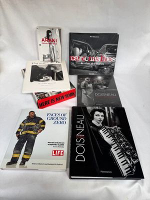 plusieurs livres posés sur un lit, avec un drap blanc en arrière-plan