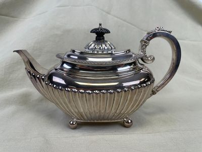 une théière en argent avec son couvercle, posée sur une table