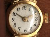 a close up of a gold wrist watch on a brown surface