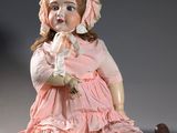 poupée assise par terre, vêtue d'une robe rose et d'un bonnet