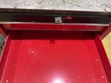 a red tool box with a red handle on the floor