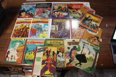 beaucoup de bandes dessinées sur la table, à côté d'un ordinateur portable