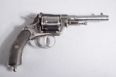un revolver argenté posé sur une surface blanche, avec un fond blanc