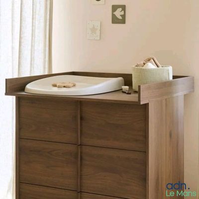 une commode en bois avec un lit de bébé blanc dans un coin