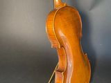 an old violin sitting on a stand against a gray background